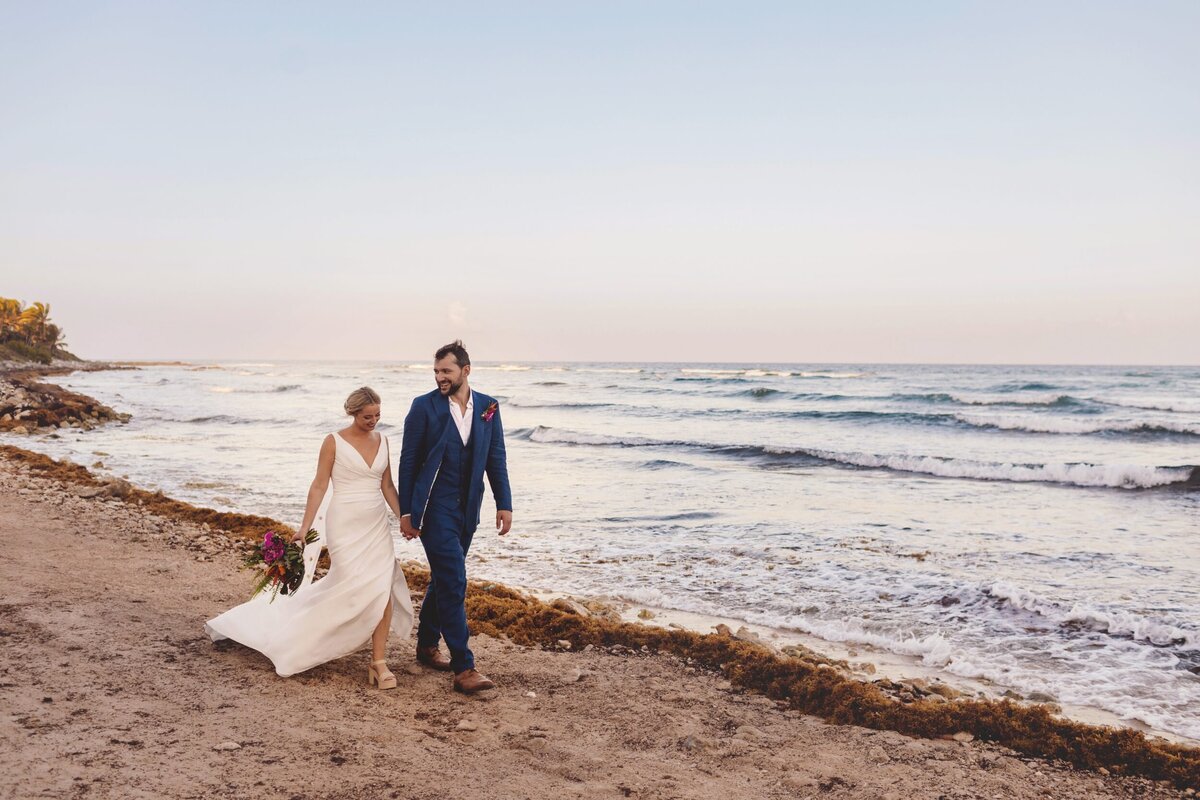 Bride and groom walking down beach at wedding in Riviera Maya
