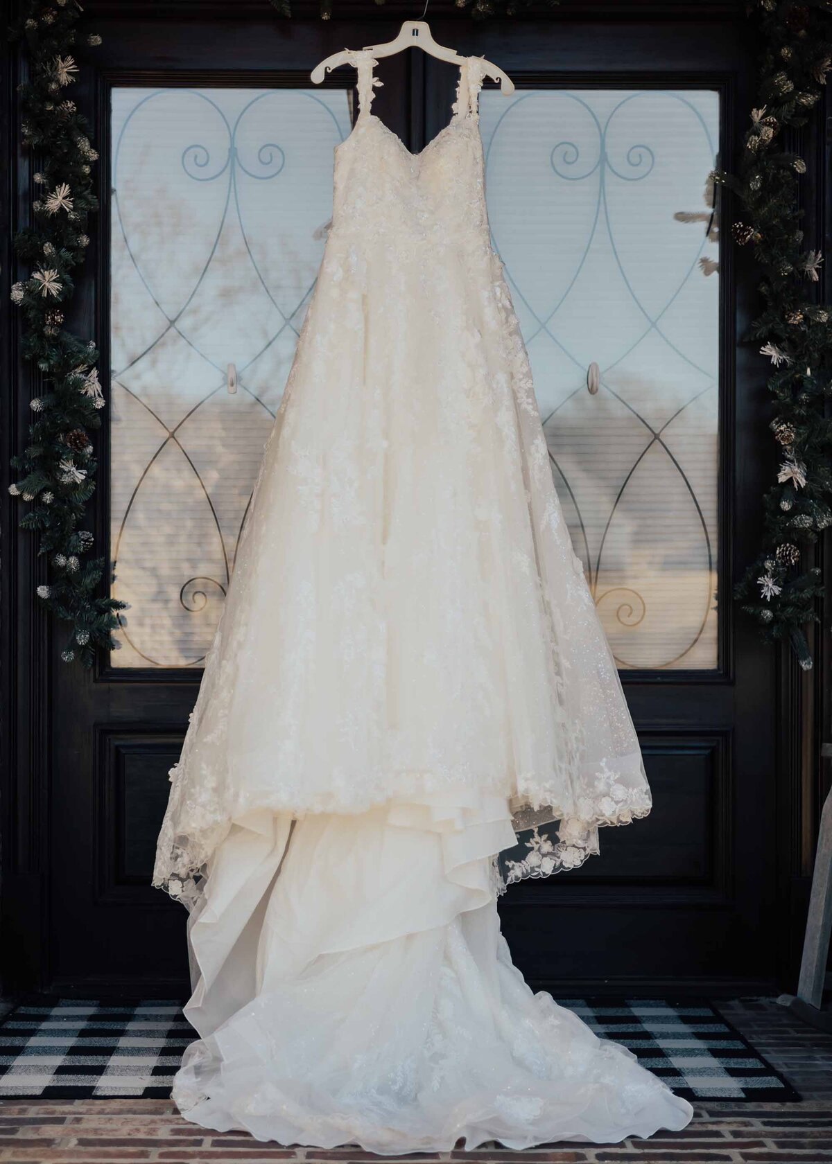 Maddie Rae Photography big fluffy wedding dress hanging from the light fixture of the front porch of the venue