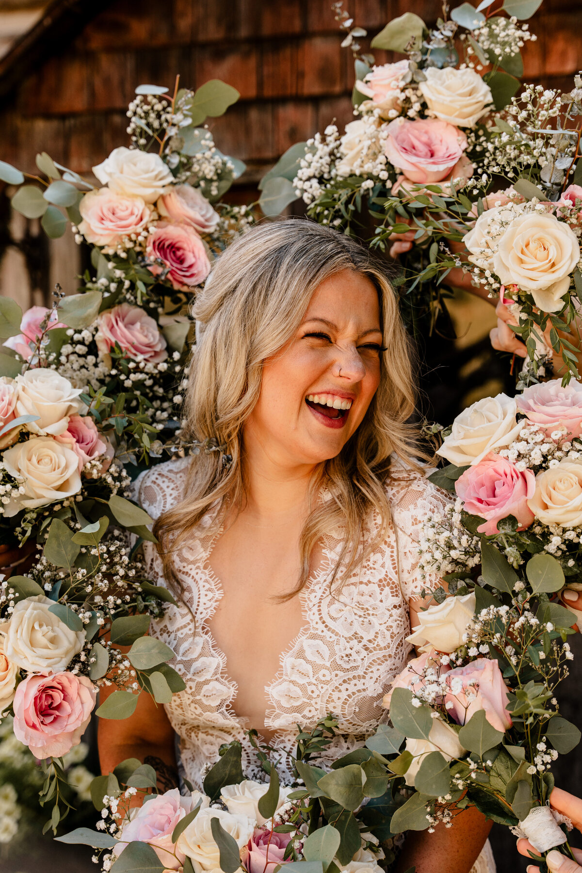 The bride laughs, surrounded by all the bridesmaids' flower bouquets.