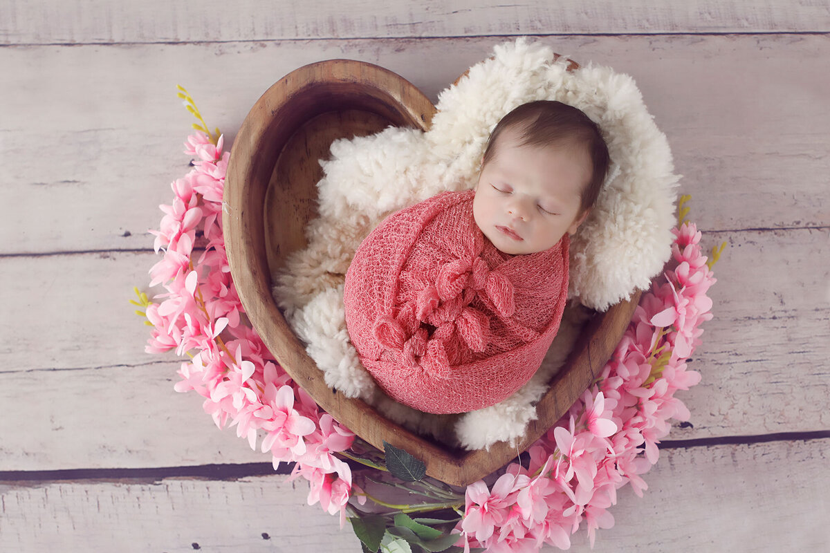 newborn-gils-6-days-old-wrapped-up-in-a-pink-wrap-with-flowers-and-a-heart-bowl