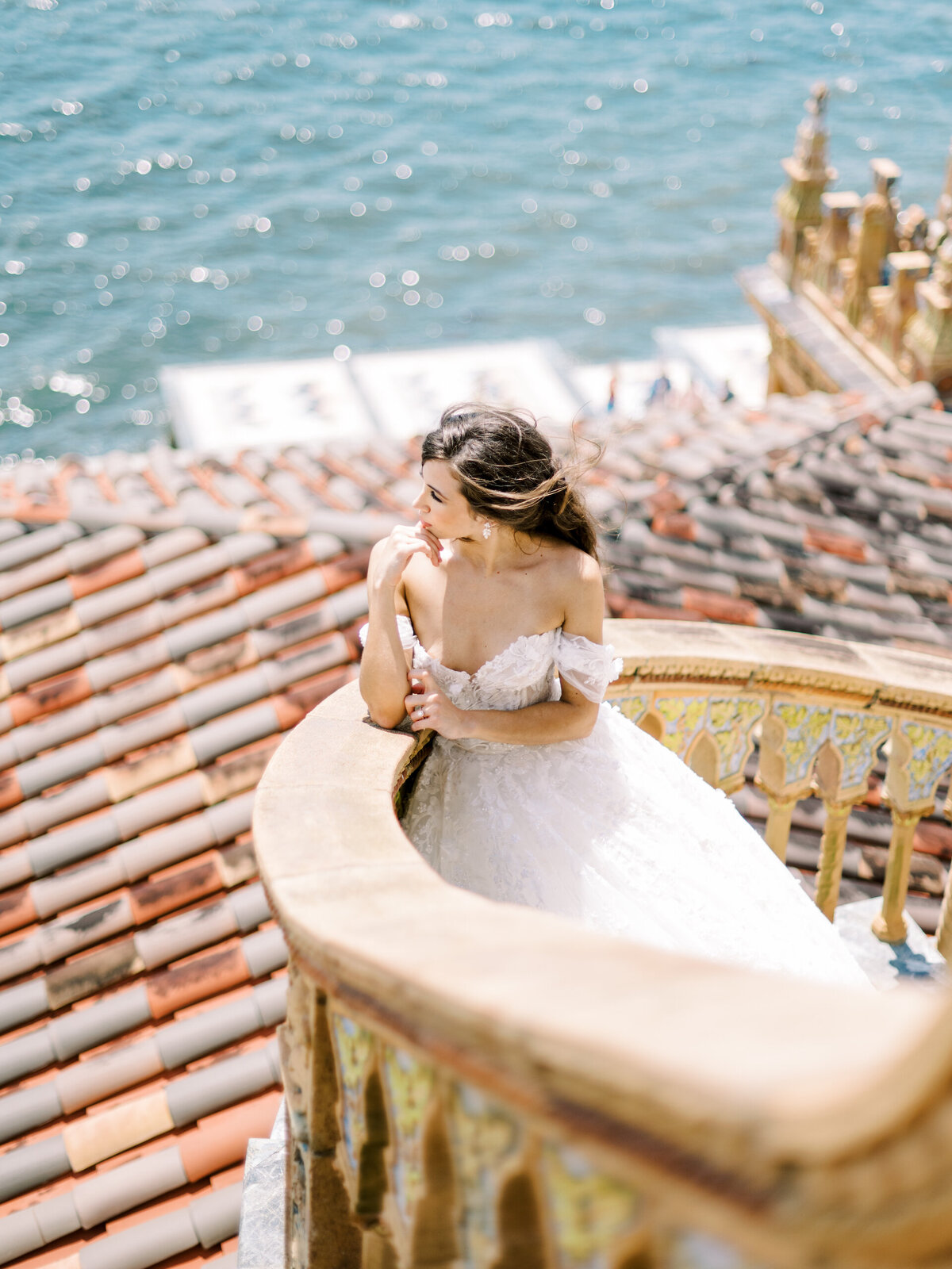 bride looking out at the water from a staircase