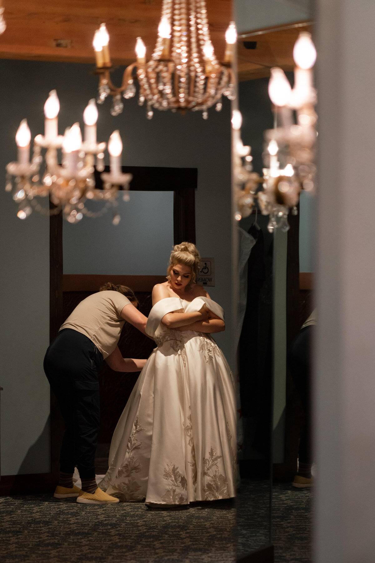 Bridesmaid helps bride button up her dress.