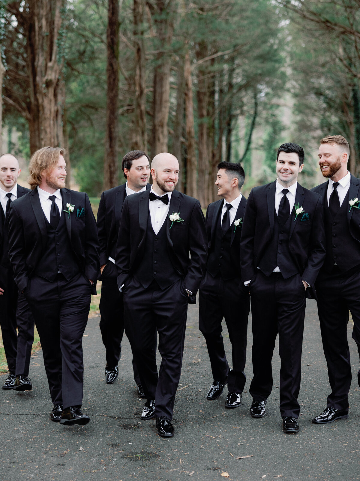 A groom walking with his groomsmen as they laugh and talk with one another