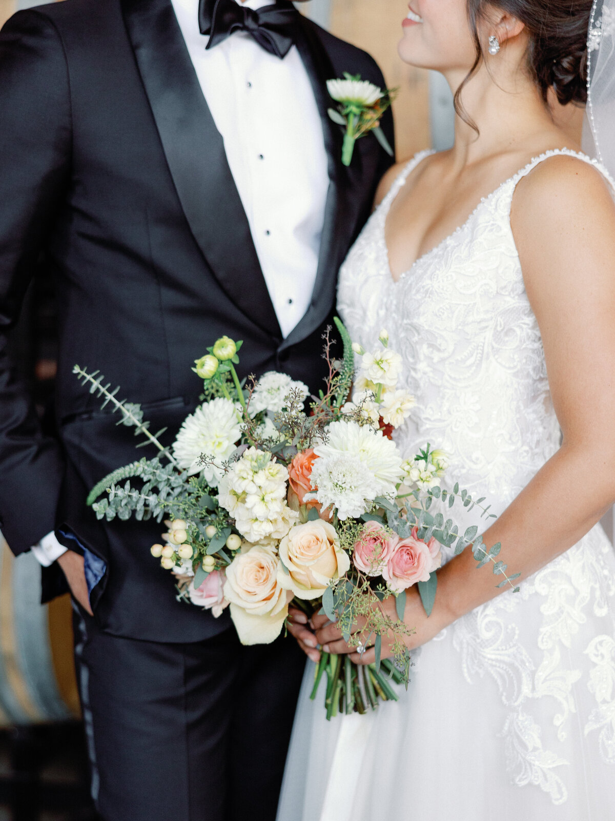 A close up of the bride's bouquet as she looks into the eye of her groom