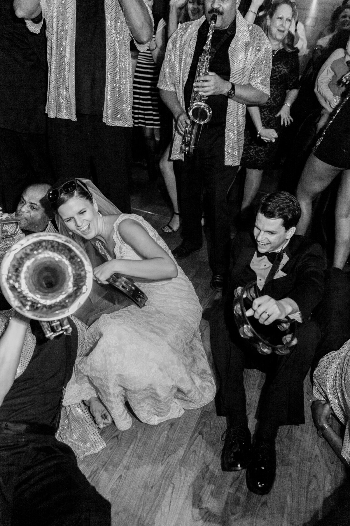 A bride and groom join the band on the dance floor for this candid black and white wedding photograph