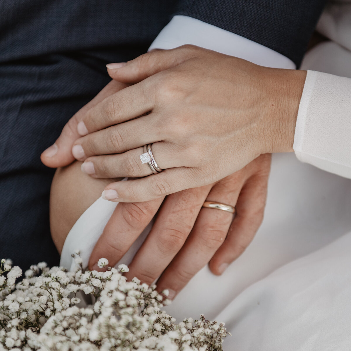 jackson wyoming photographer captures detail shot of bride and groom's hands holding each other and showing their wedding rings