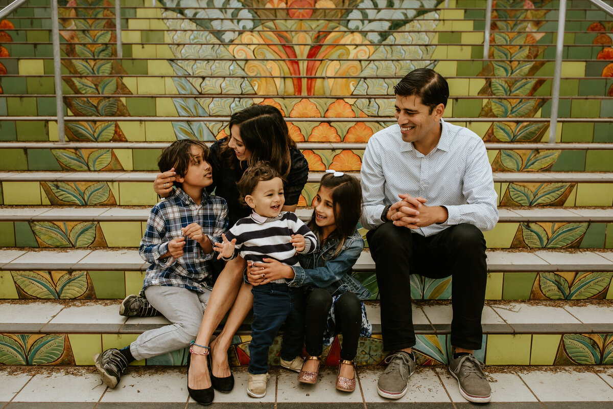 Lifestyle portrait of family of 5 sitting on rainbow colored mosaic steps