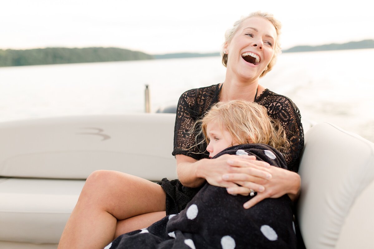 A mom laughing with her daughter on a boat in a lake in KY.