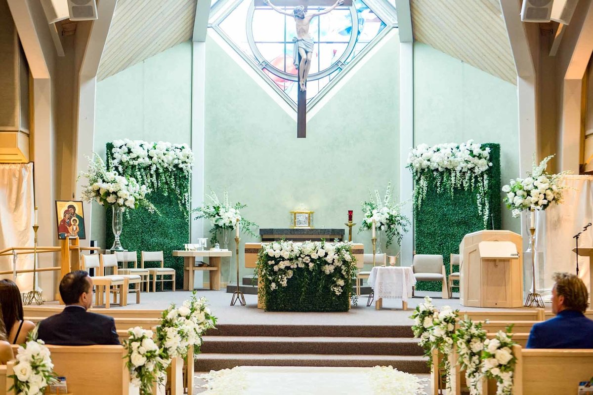 Wedding ceremony church with white and green floral and greenery walls