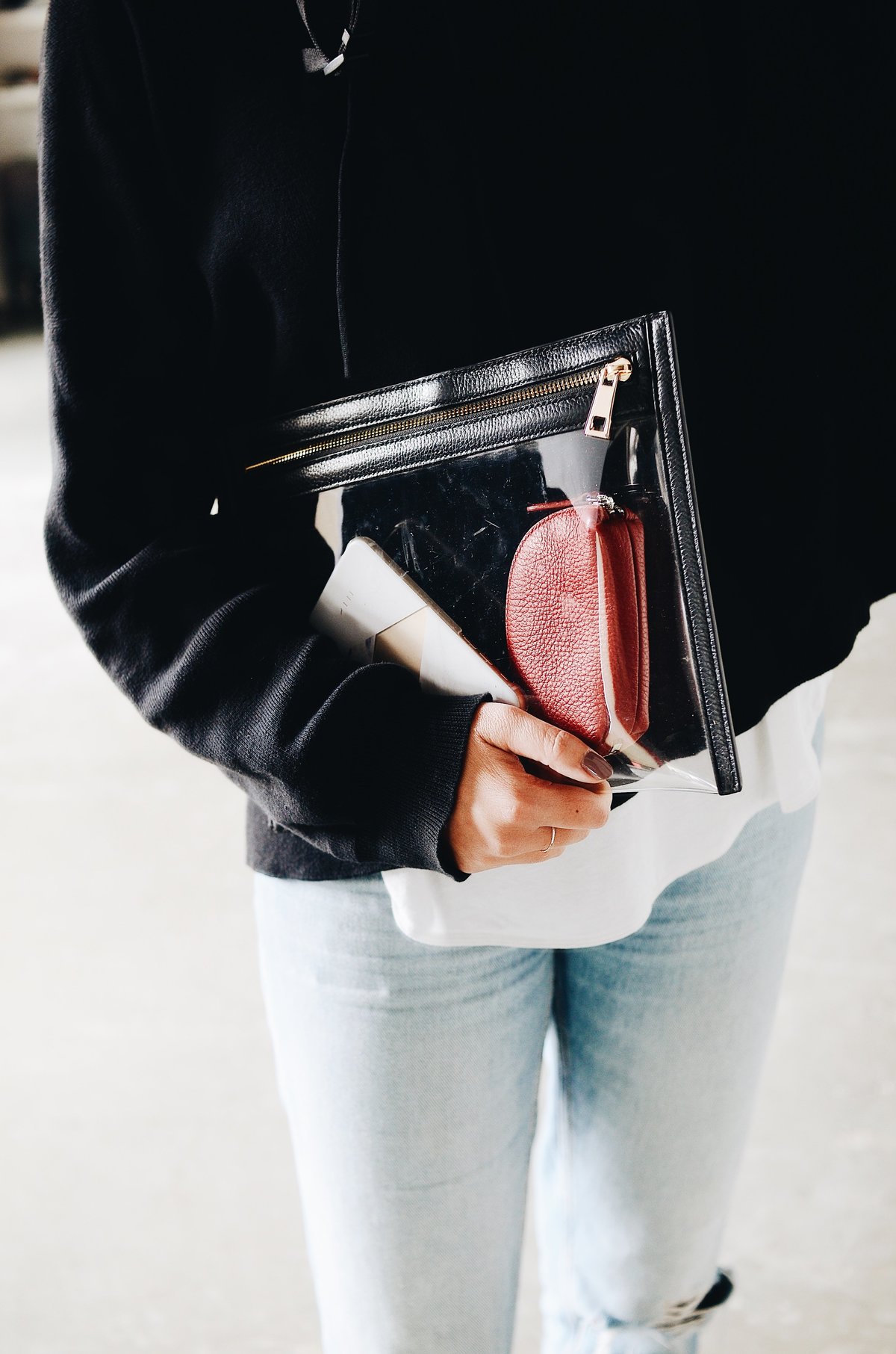 A woman holding a clear clutch with some travel essentials