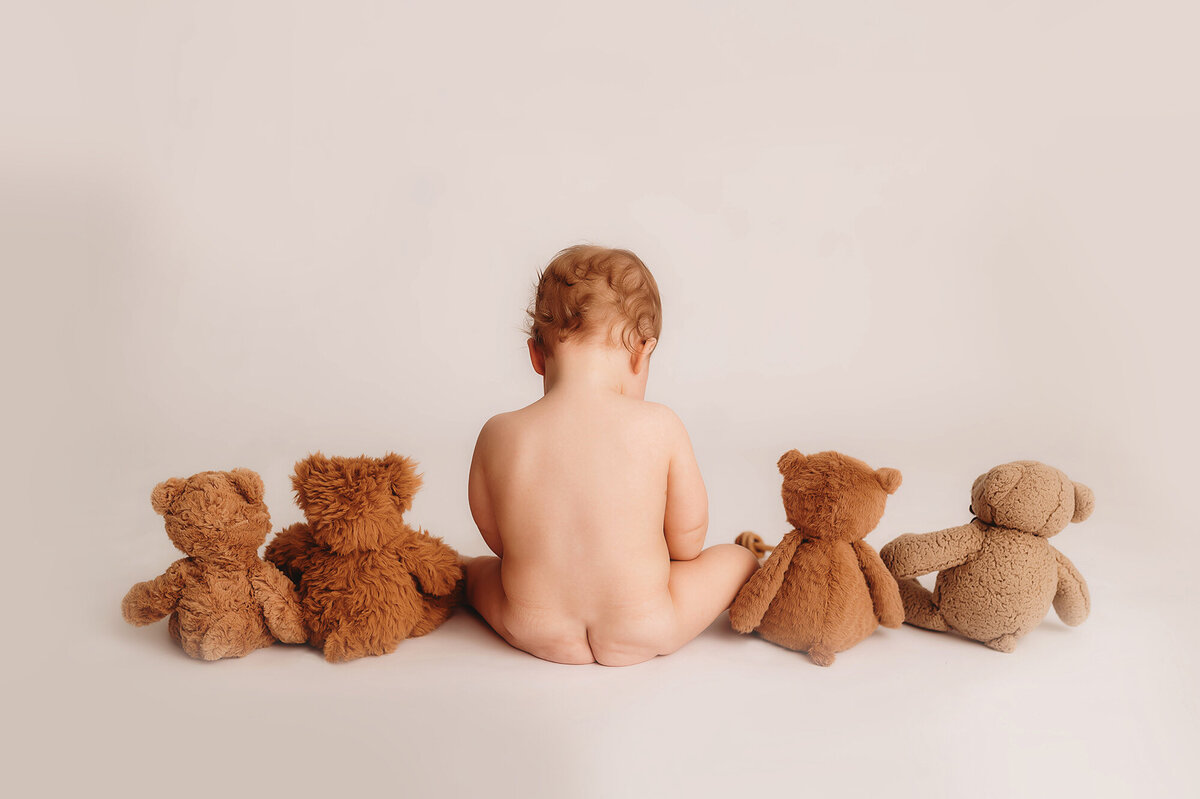 Baby sits with stuffed bears during first birthday photoshoot in Asheville.