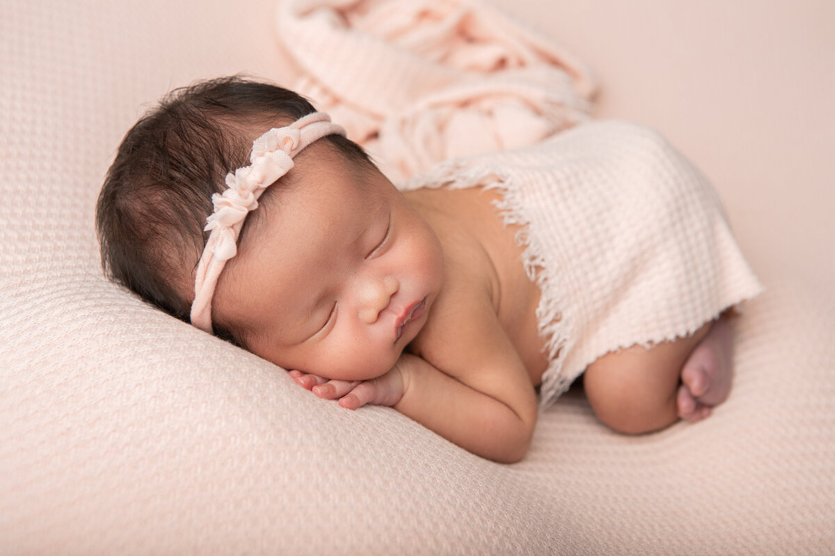 Bum up studio newborn table pose on a pink backdrop