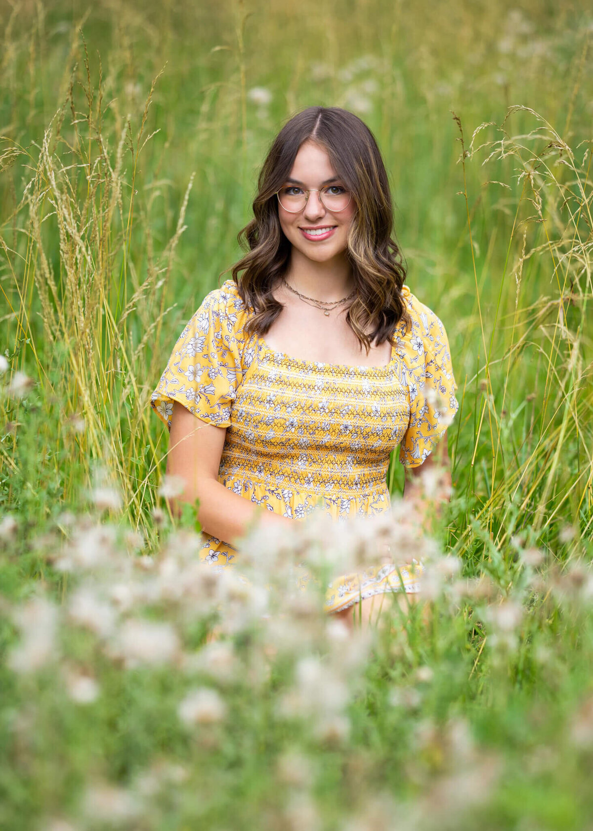 teenage girl in yellow sun dress sitting in a tall grassy field