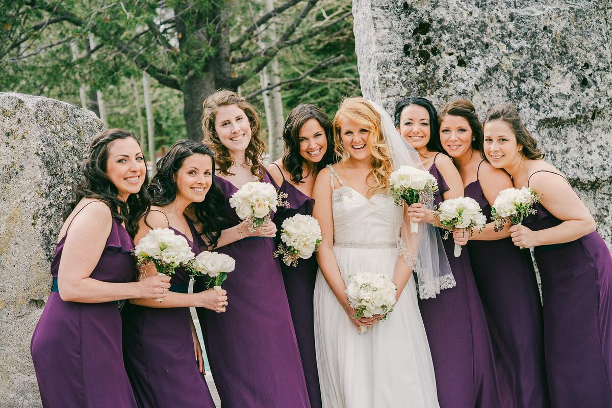 bride and her bridesmaids posing together in front of granite boulders at PlumJacks Palisades Tahoe