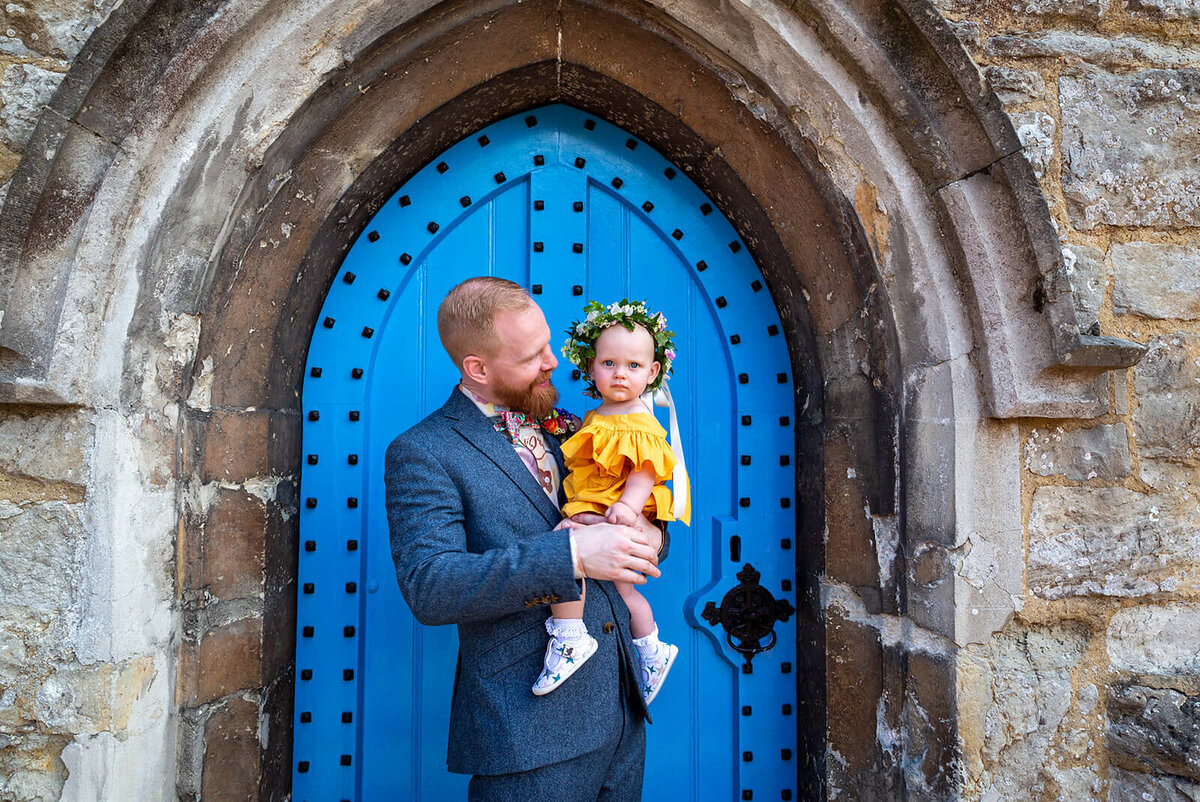 Groom holding daughter in front of church Kent