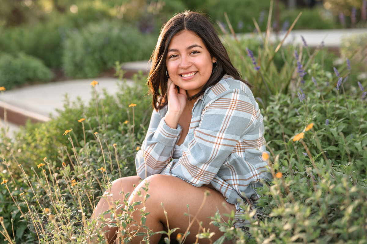 Girl smiles among the flowers during senior pictures in San Antonio.