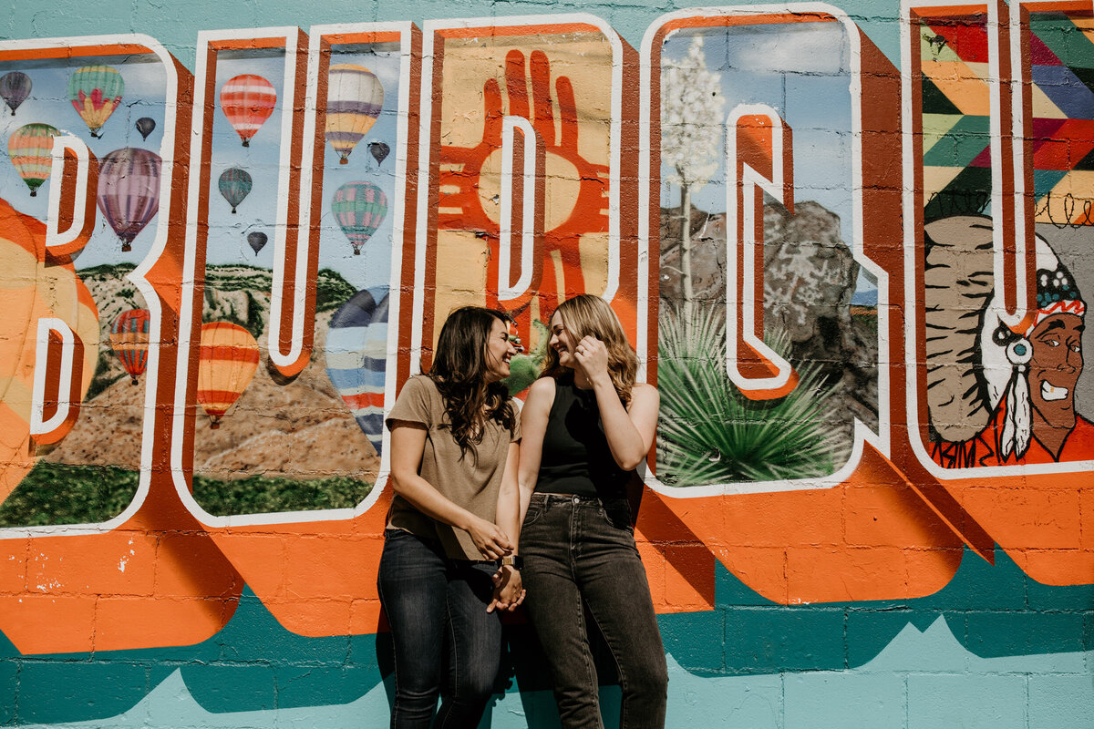 lesbian couple standing together in front of a colorful wall in downtown Albuquerque
