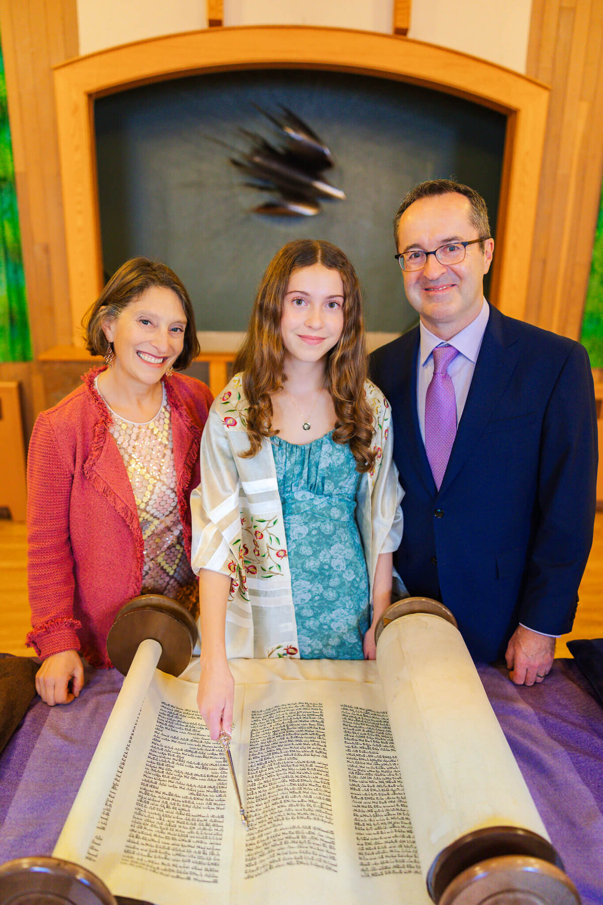 A mother and father stand with their daughter at the torah