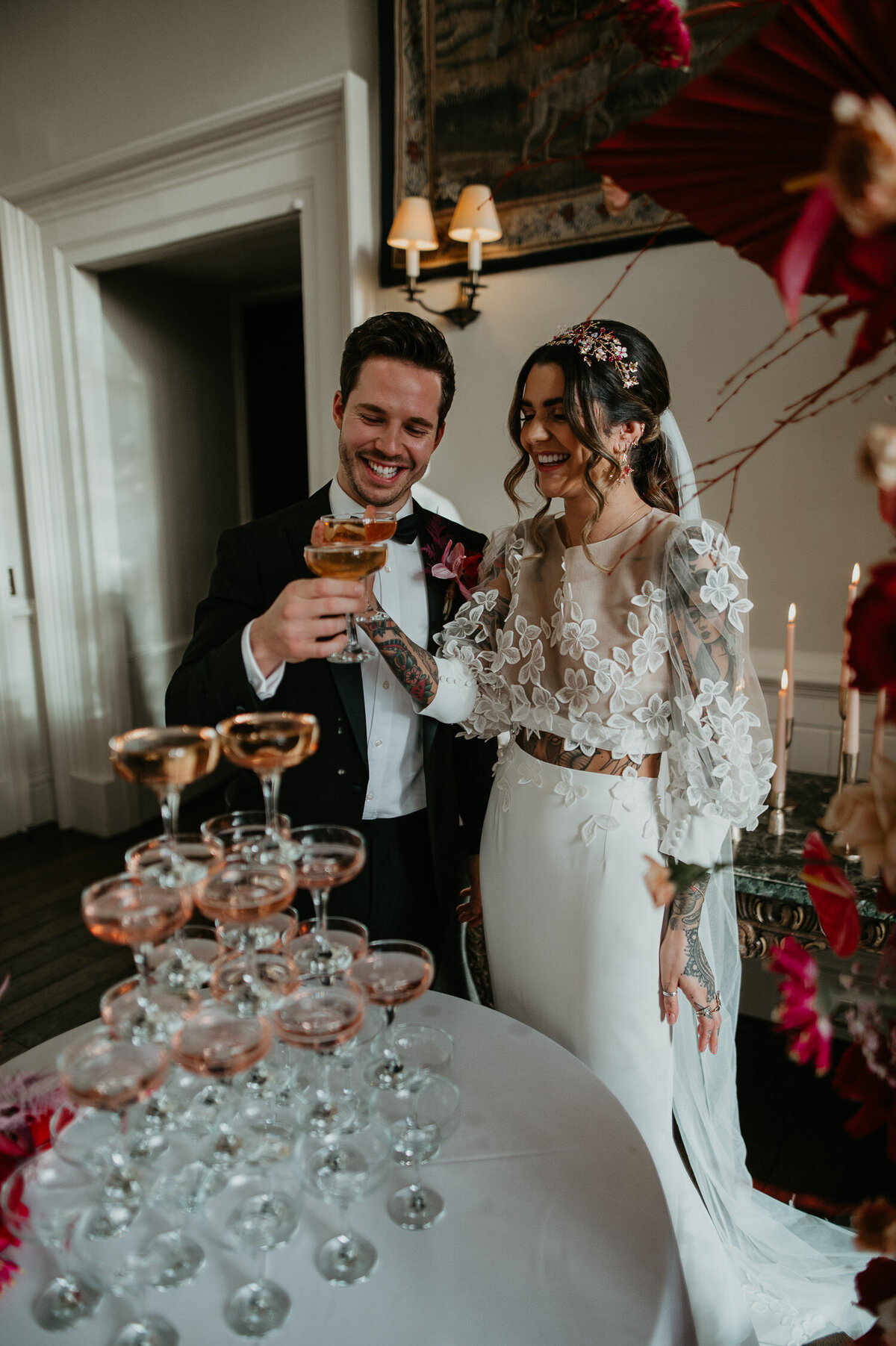 A couple take a Sio of champagne after pouring their champagne town. The bride is wearing a stunning two piece and the groom is wearing a black tie suit.