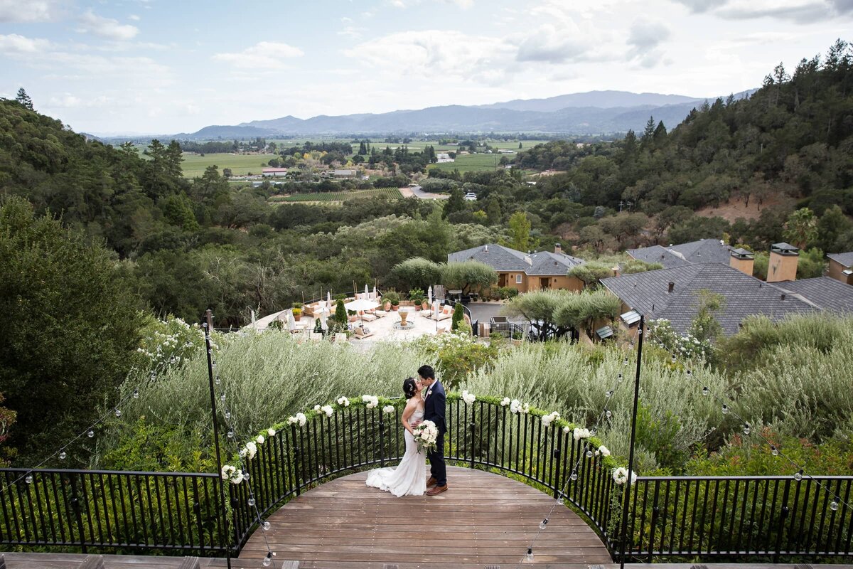 newlyweds kissing on a terrace overlooking Napa Valley, CA