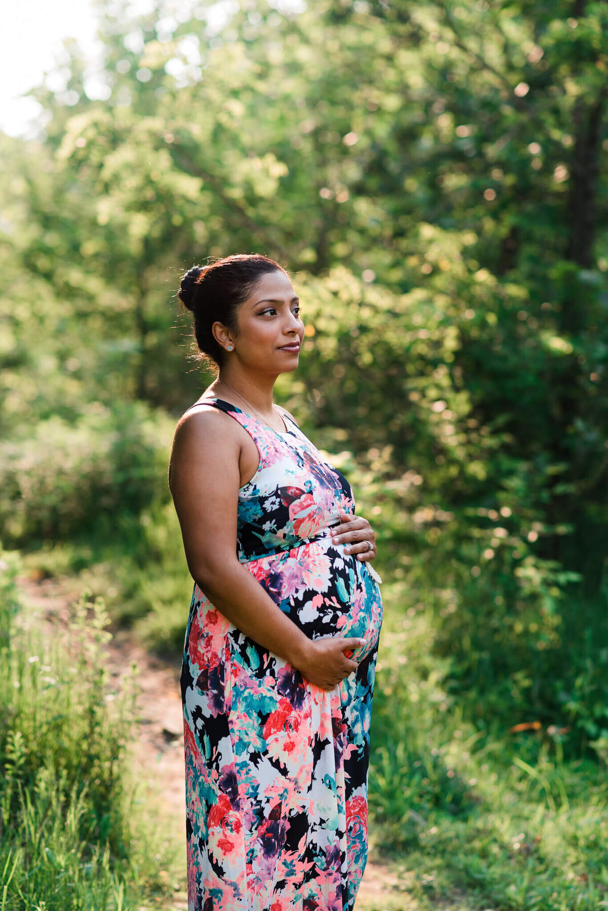 A woman wearing a floral maxi holding her bump in the spring