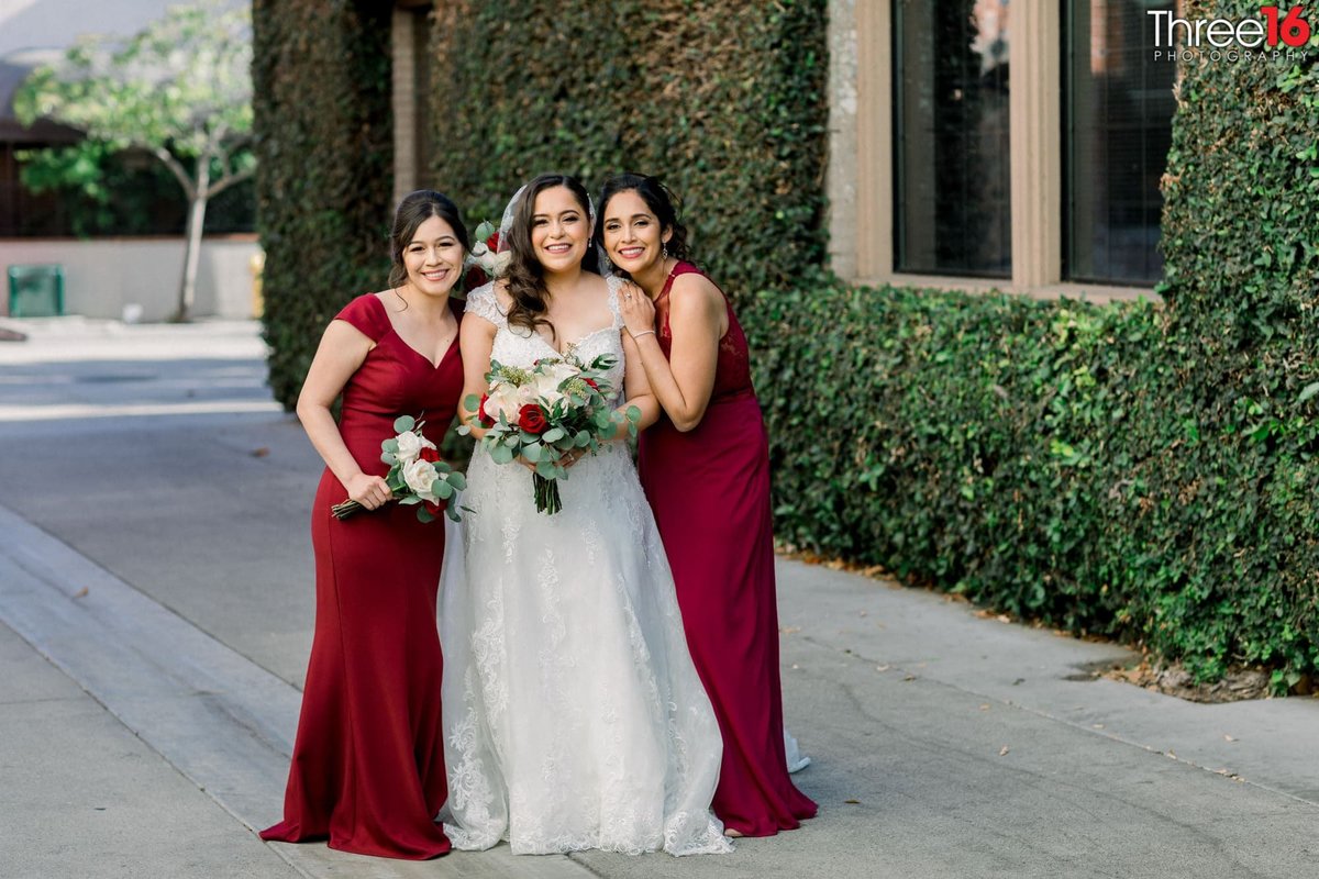 Bride posing with her Bridesmaids who are decked out in their maroon colored dresses