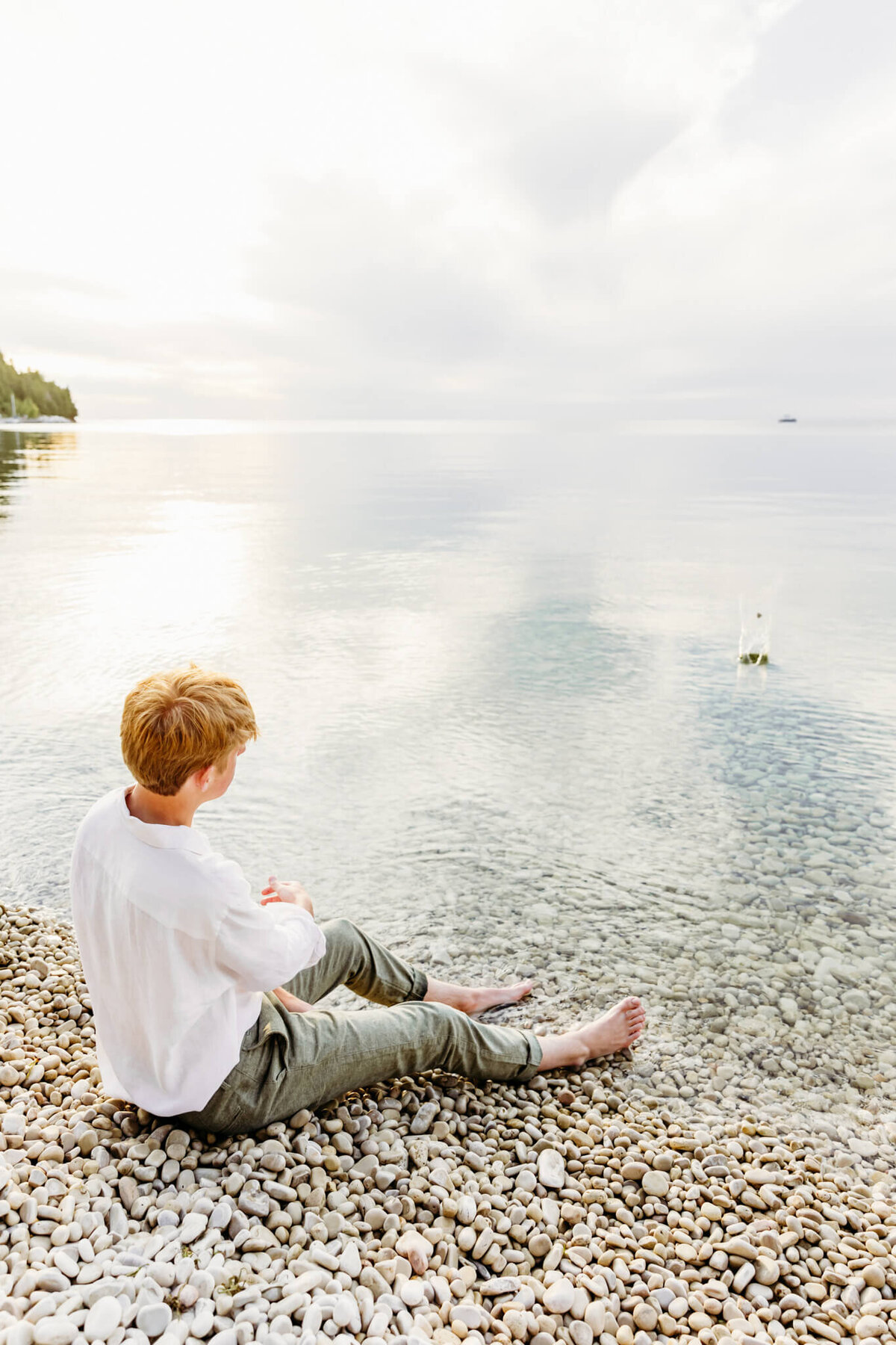 teen guy skipping a stone into the lake for senior portraits