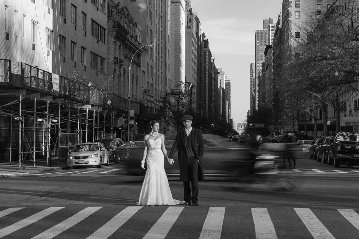 bride and groom dressed in wedding attire standing in sunlight on crosswalk of nyc street by cait fletcher photography