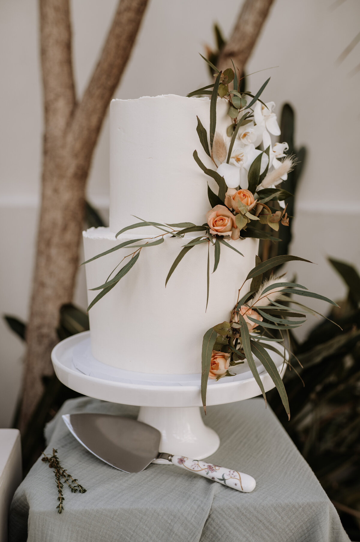 Simple white wedding cake with botanical flowers in Gunnersbury Park orangery