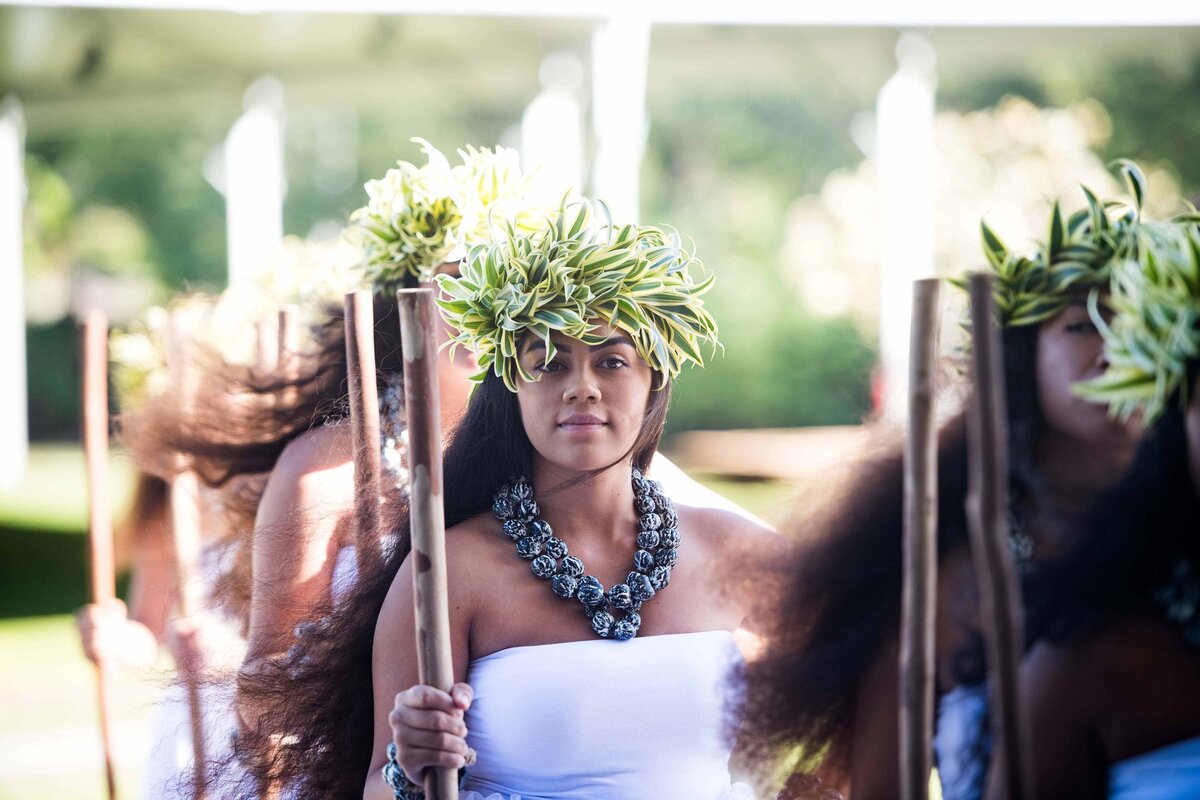 A female Hawaiian dancer holds a stick wearing a traditional headdress and beads for a performance on the Big Island