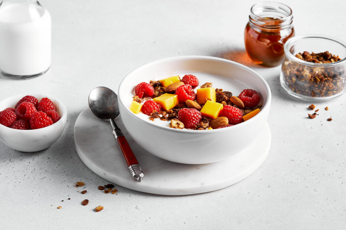 Fruit and granola on top of a bowl of yogurt.