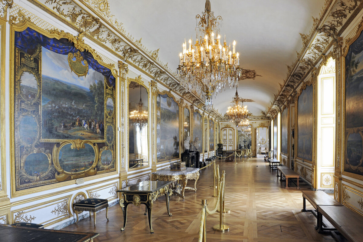 Hallway with gold decor and large paintings at Château de Chantilly