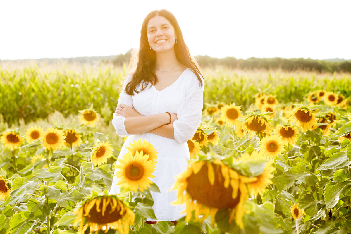 white teenage girl with light brown hair in a white dress poses in a sunflower field Sunflower Valley Farm Hudson Valley senior portrait session North Rockland High School photographer