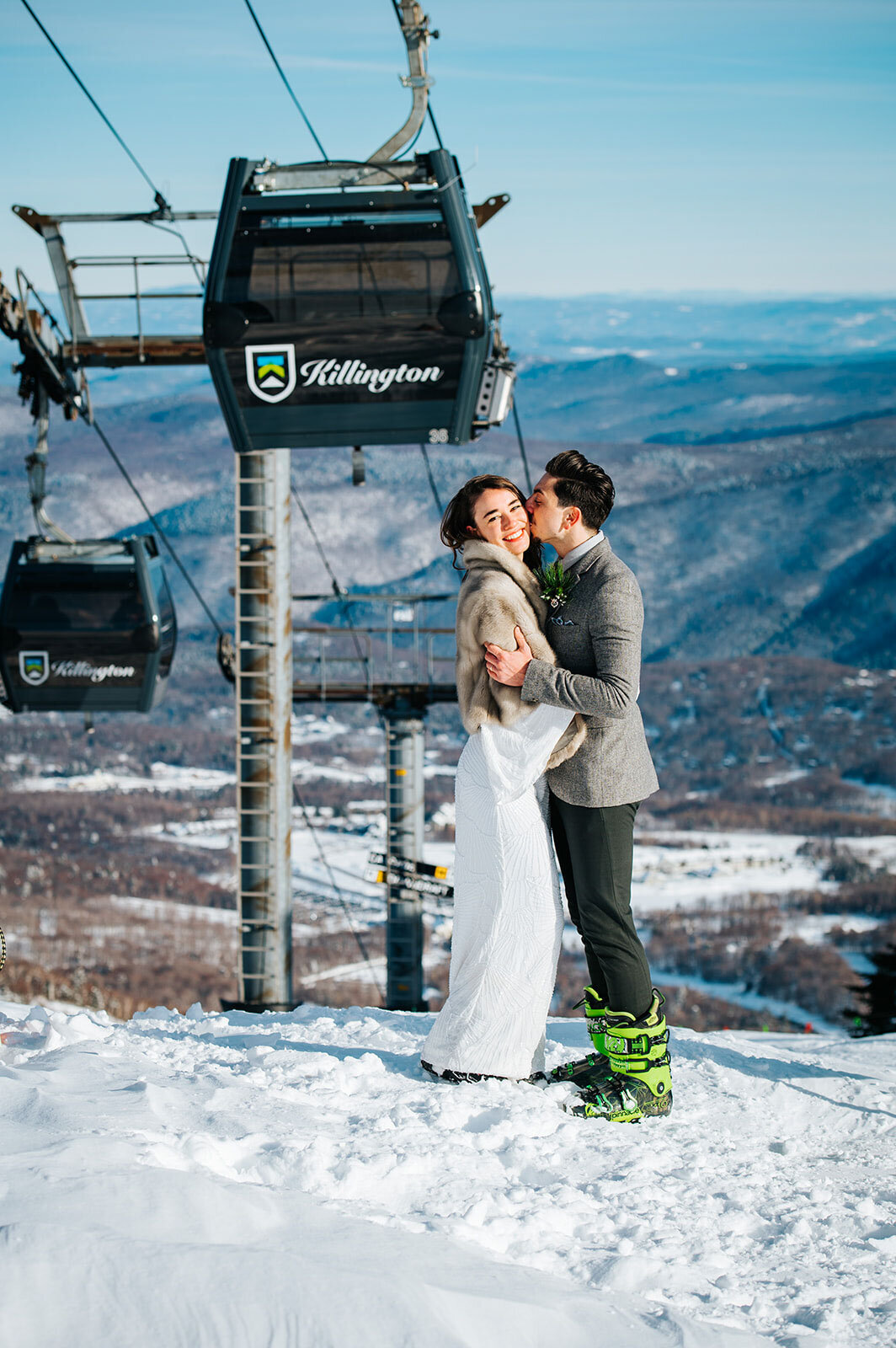 couple on skis in front of gondola chair lift at winter wedding in killington vermont