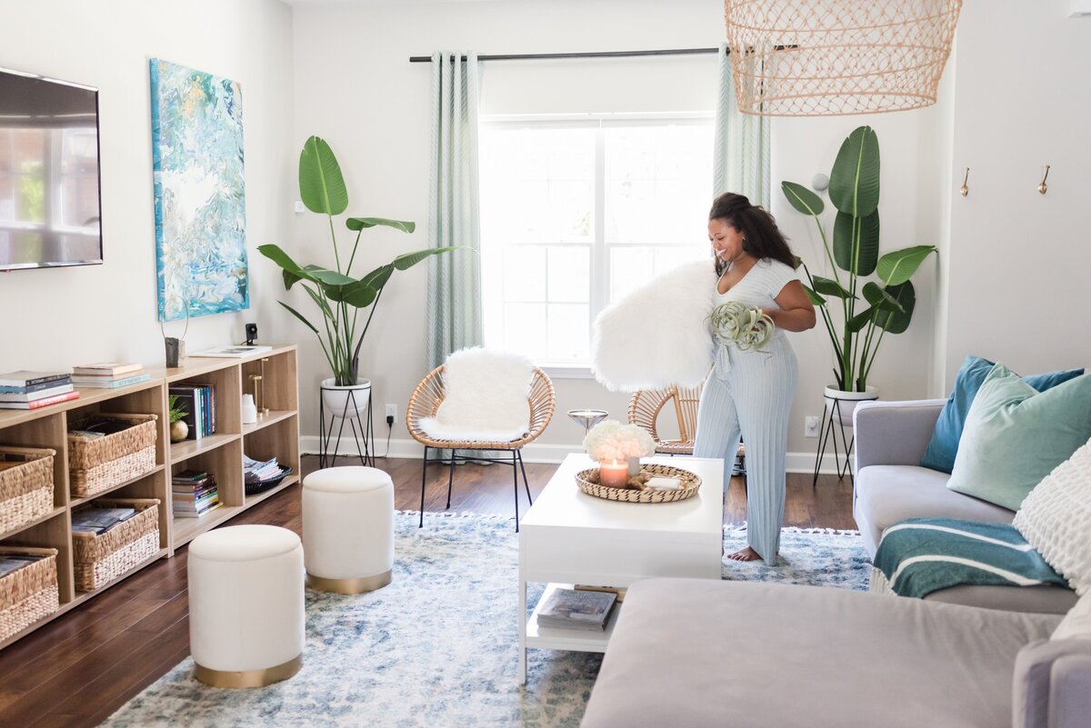 Nashville interior designer walking around her living room with a plant and a pillow in her arms
