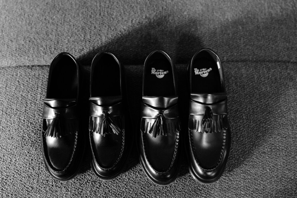 Two pairs of black shiny wedding shoes for a queer wedding.