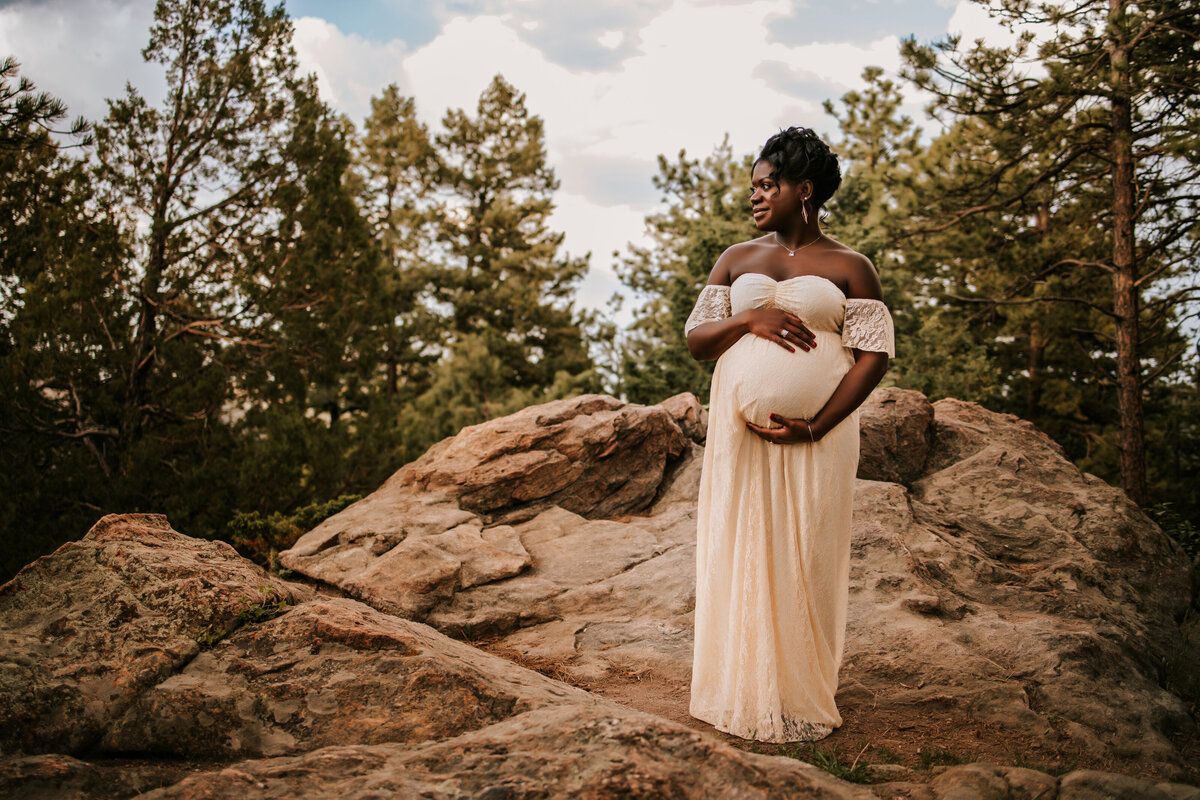 pregnant mom wears a long white dress in the fall for maternity photos in denver colorado