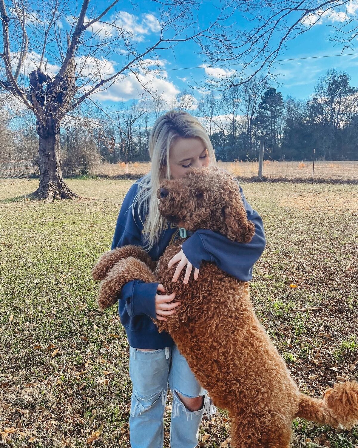 Girl stands with goldendoodle dog