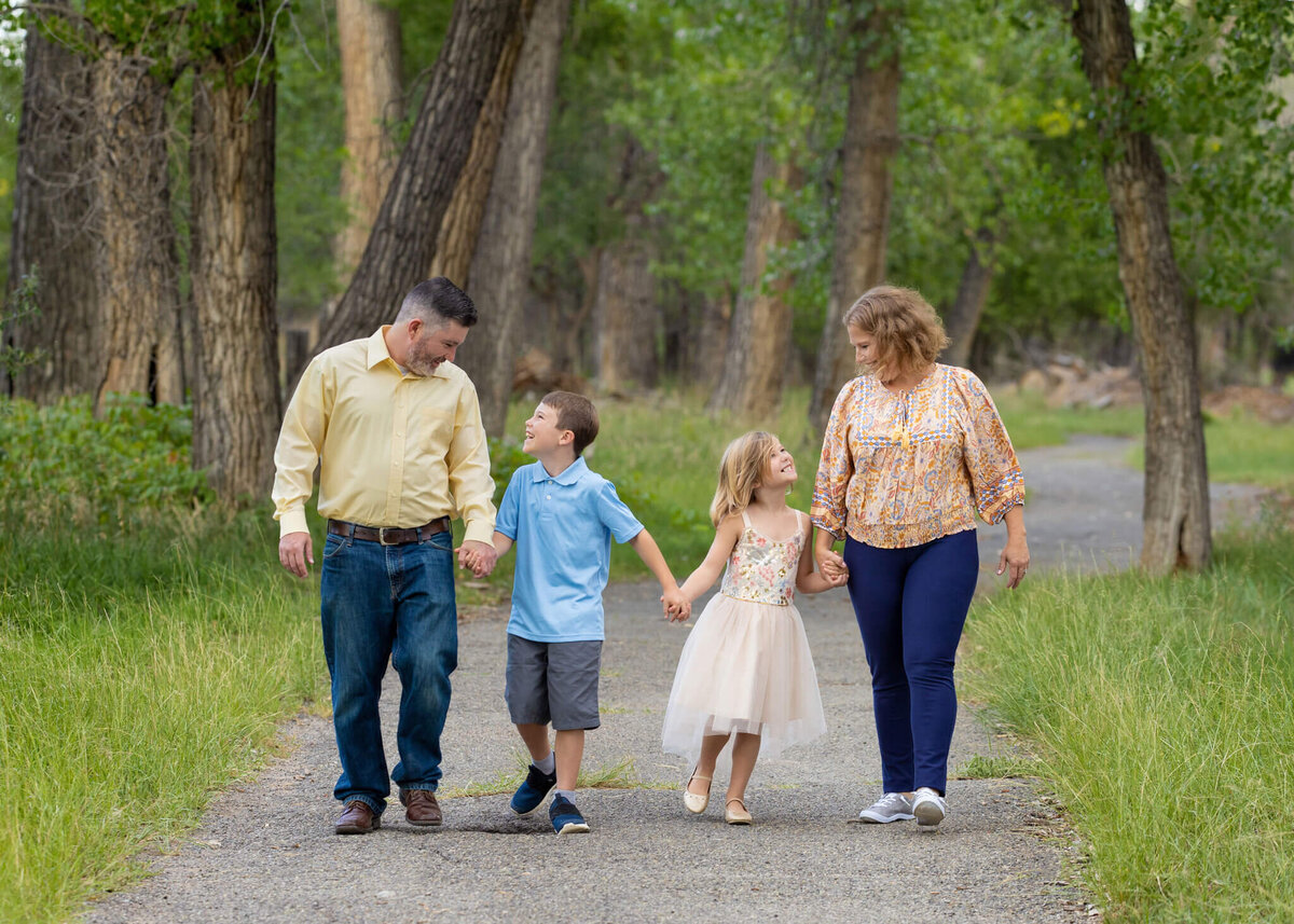 family of four looking at each other while walking donw a path in City Park Pueblo, Colorado