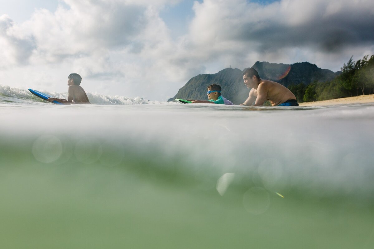 dad and teenage kids surfing at waimanalo beach