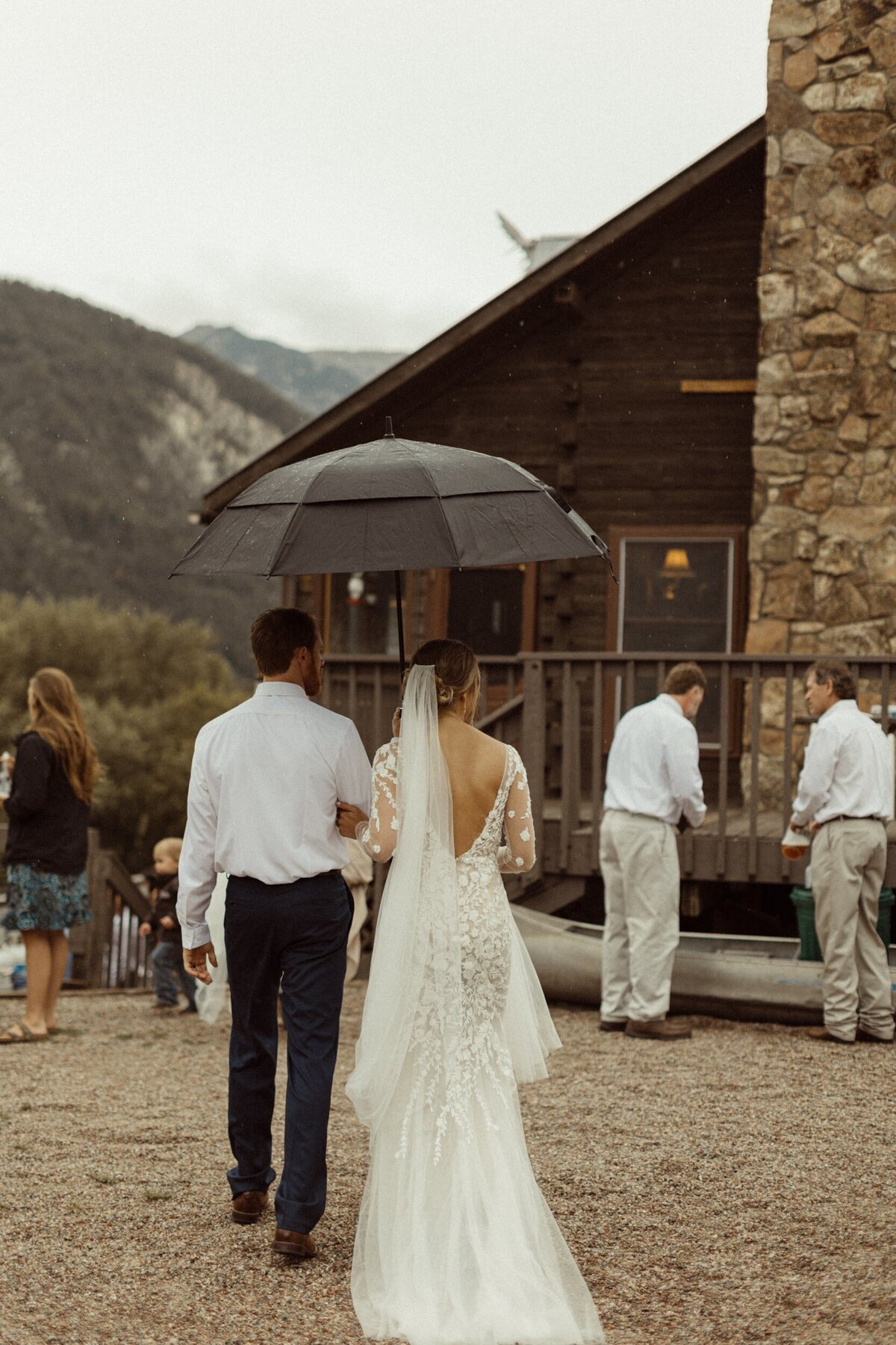 A bride and groom walking into their intimate wedding in colorado holding an umbrella in Marble Colorado