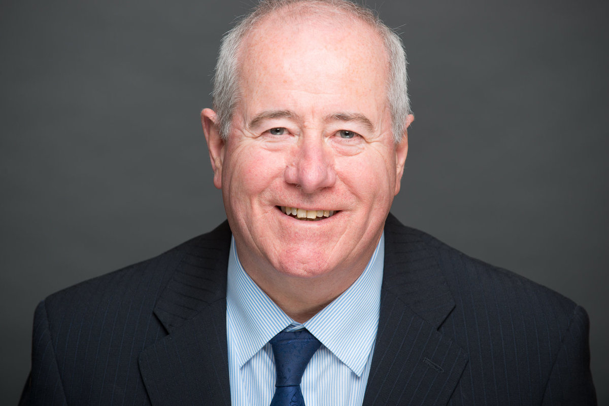 Profile photo of a male company director smiling in navy suit and tie
