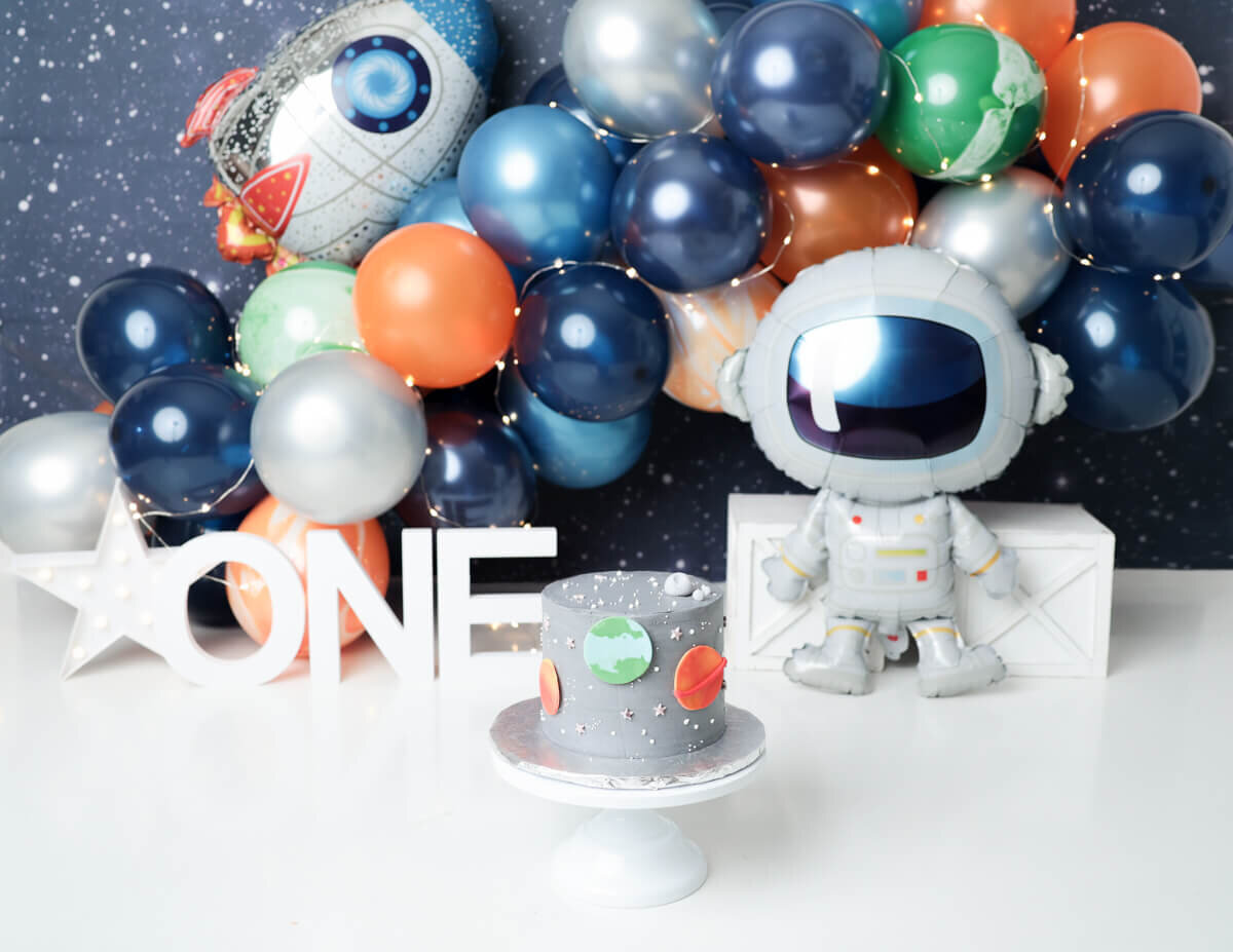 A space themed cake smash, surrounded by colorful decorations and a starry backdrop in Rochester, NY.