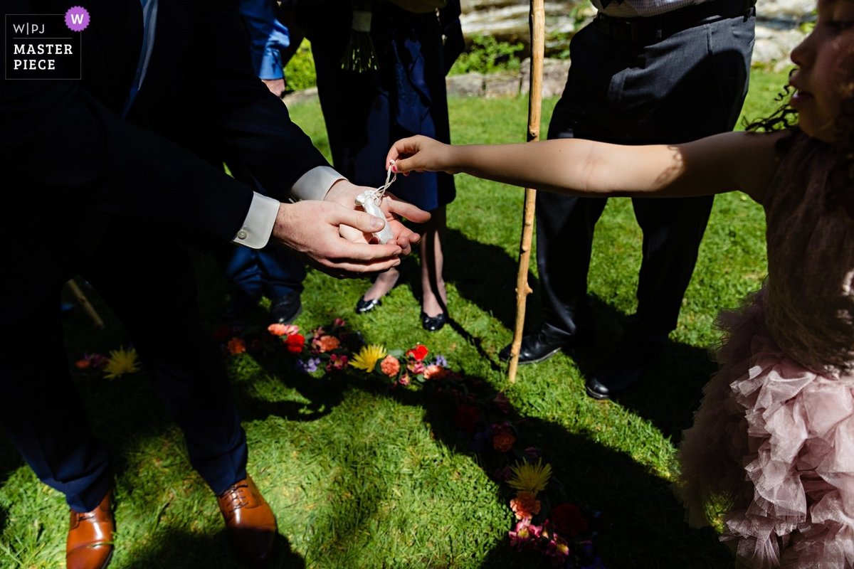 Jackson New Hampshire elopement photographer the grooms niece passes the rings to the groom