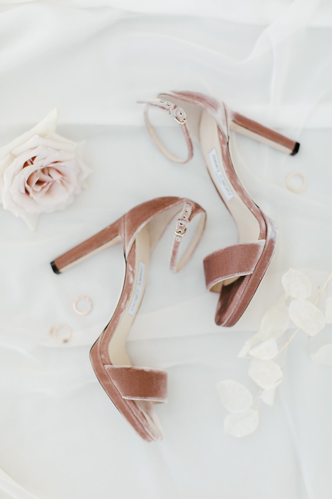Pink shoes are styled in a flatlay with dried blooms.