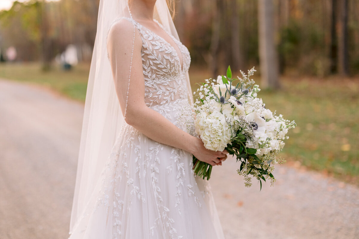 Wedding Photographer, a bride in her dress holds a bouquet of flowers on a country road