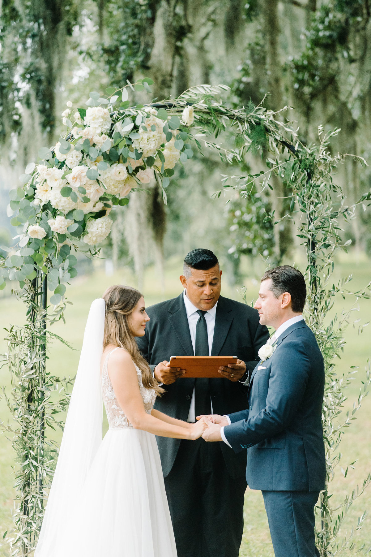 Bride and Groom under Greenery and Asymmetrical Ivory White Floral  Arbor