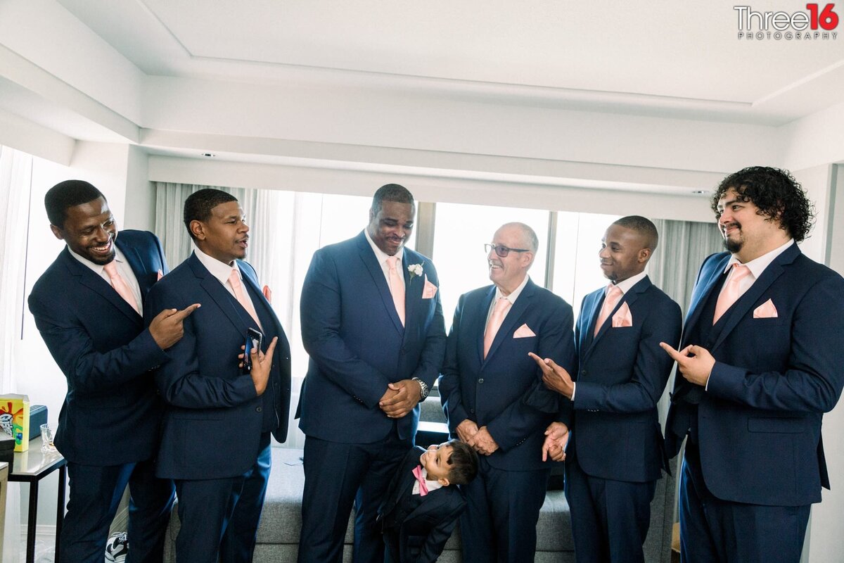 Groomsmen point to the Groom as he is the man!