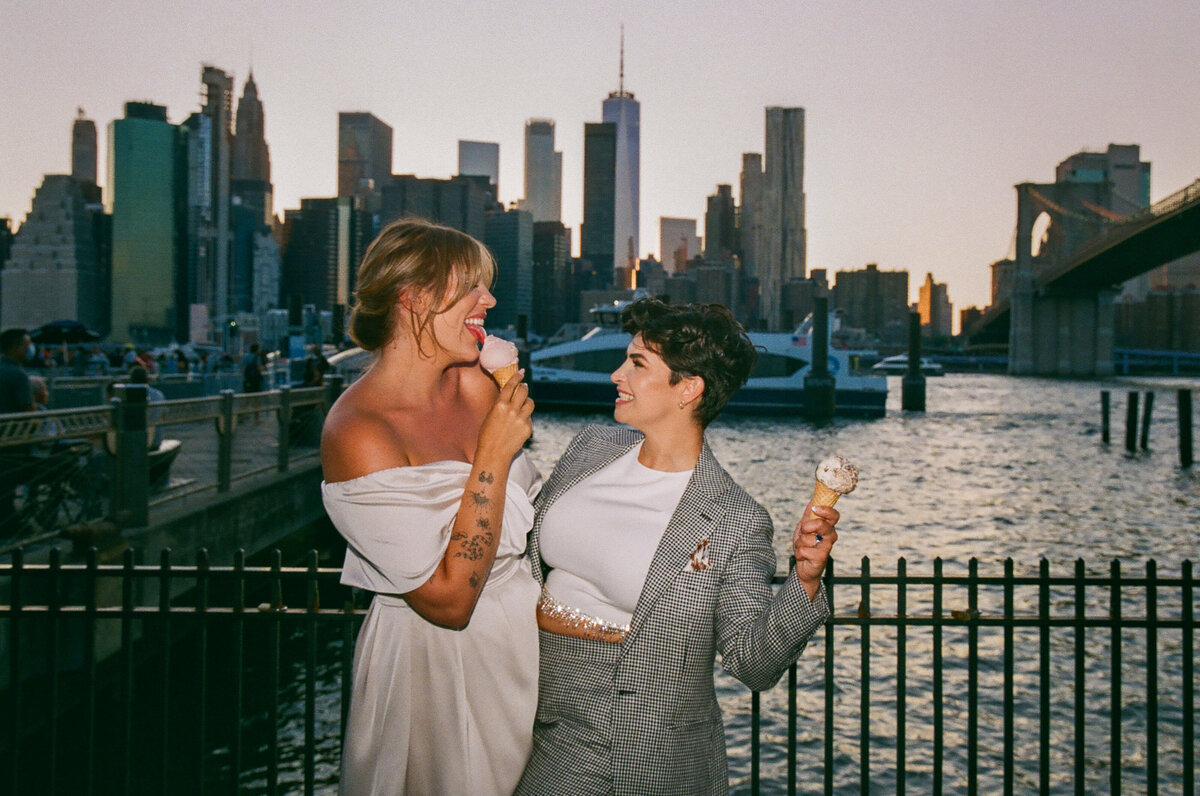 A couple standing on a bridge eating ice cream together.