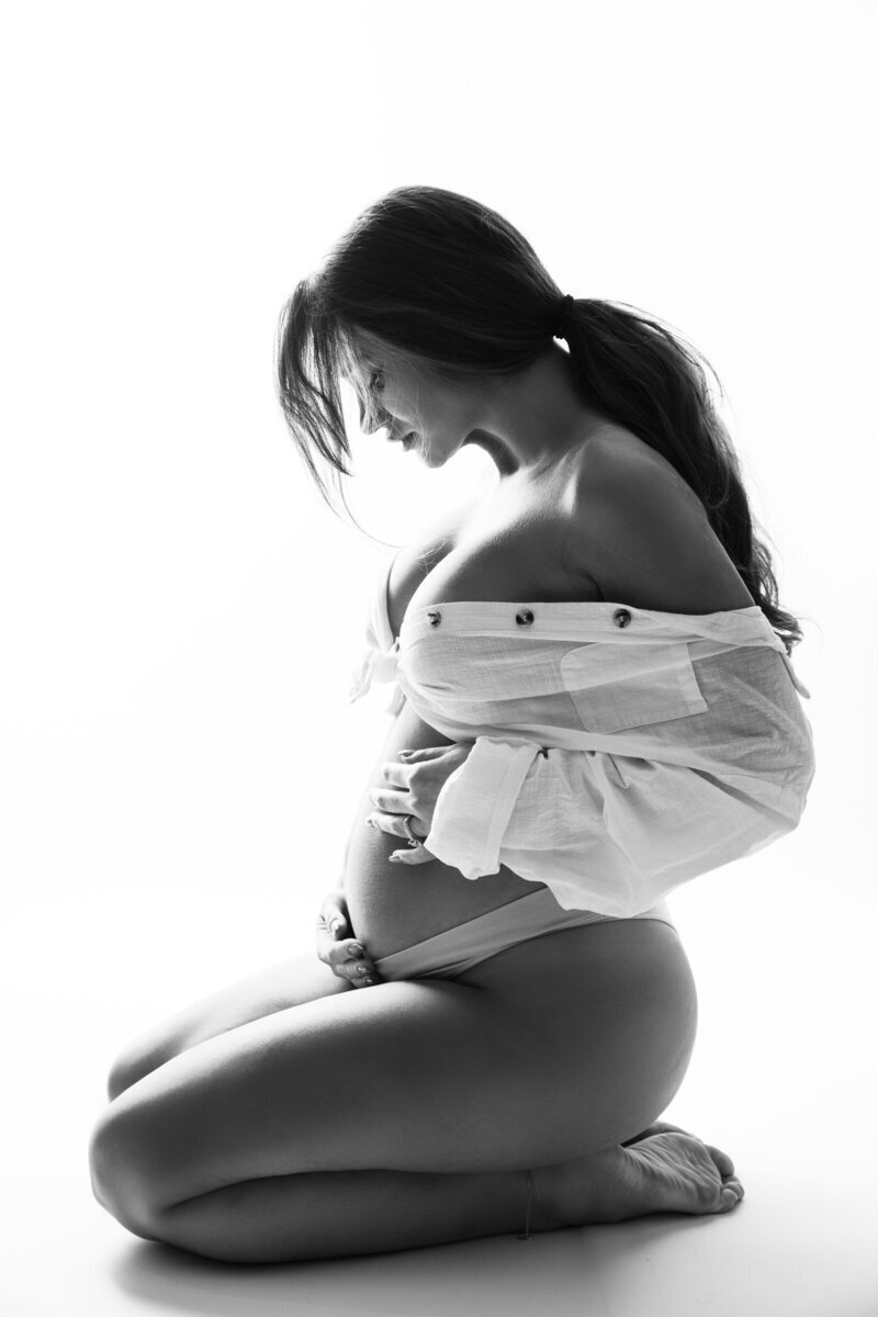 Pregnant woman sitting on ground holding baby bump, by nj maternity photographer
